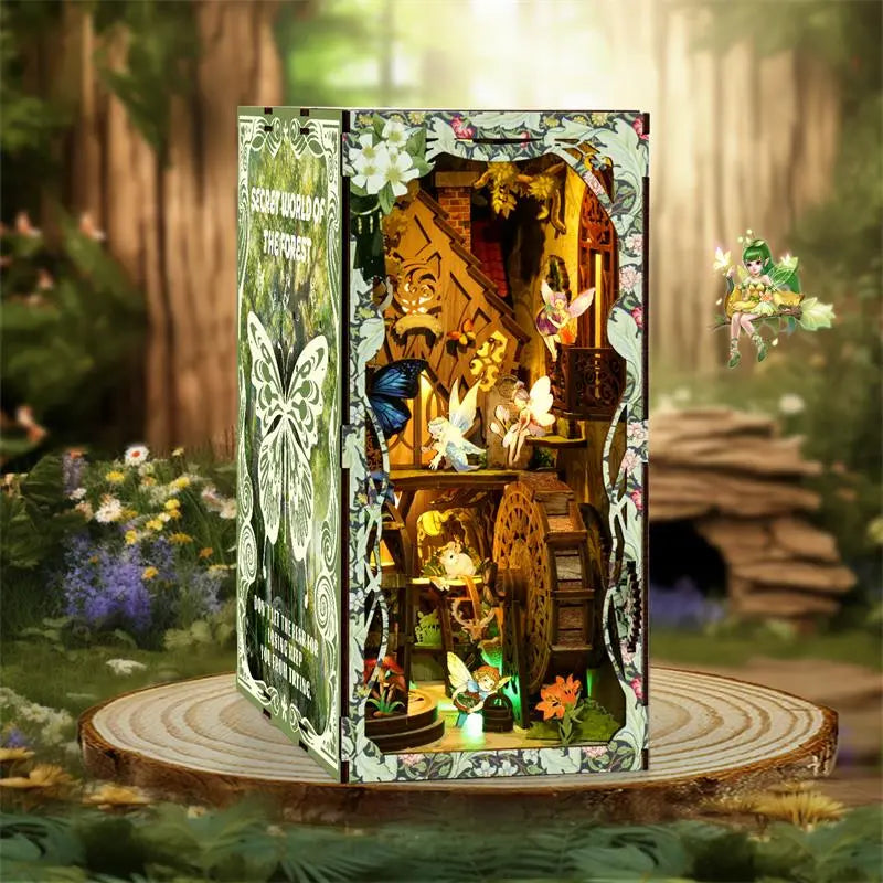 【Secret World of the Forest】 book nook placed on a wood slice base with deep forest and grass background; left side features white butterfly cutout panel, fairies and blue butterflies flying in the miniature forest, creating a natural fairy-tale vibe