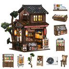 【Kasuga Grocery Store】 DIY miniature model fully assembled, showing front two-story pitched roof, dark gray tile texture, openable sliding doors with lattice windows, and red lanterns on lintel