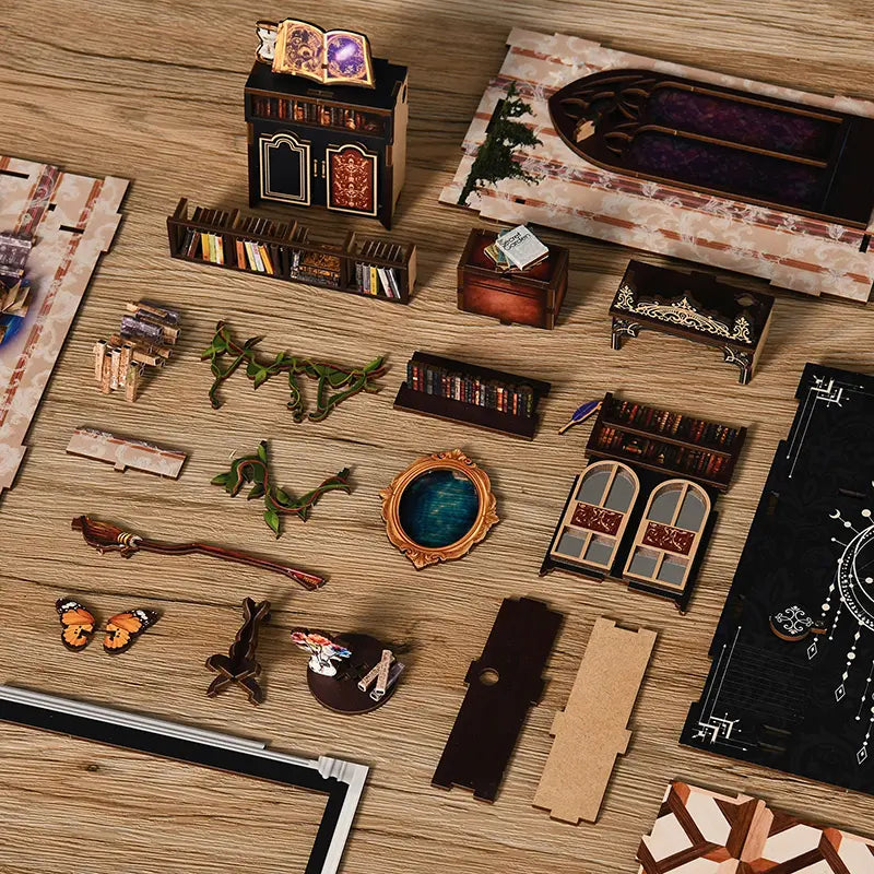 【The Realm of the Magic Book】 DIY kit parts top-down view: includes UV-printed wooden bookshelves, archway frames, round mirror components, open spellbook, flying broom, miniature flowers, and printed cardboard accessories with exquisite texture