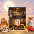 Bear Restaurant DIY miniature house – two-story handcrafted bear café displayed against a full moon pink sky with strawberries and desserts, warm amber LED lighting, bear figurines dining on ground floor and sitting at upstairs counter
