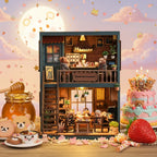 Bear Restaurant DIY miniature house – two-story handcrafted bear café displayed against a full moon pink sky with strawberries and desserts, warm amber LED lighting, bear figurines dining on ground floor and sitting at upstairs counter
