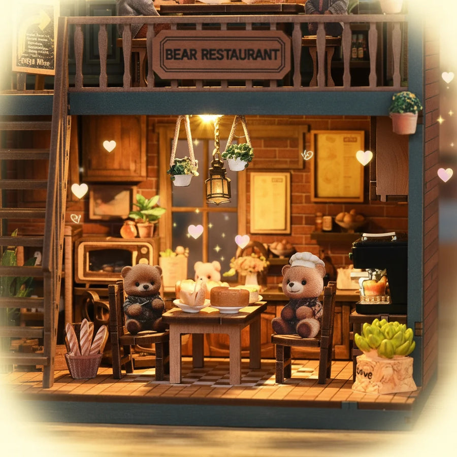 Bear Restaurant DIY miniature house ground floor interior close-up – two bear figurines dining at candlelit table, hanging macramé plant holders and vintage lantern overhead, brick wall backdrop with menu board, bread basket and succulent décor
