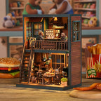 Bear Restaurant DIY miniature house side angle – exposed brick wall texture, wooden balcony railing with Bear Restaurant sign, ground floor interior with hanging plants, vintage radio and warm amber lighting

