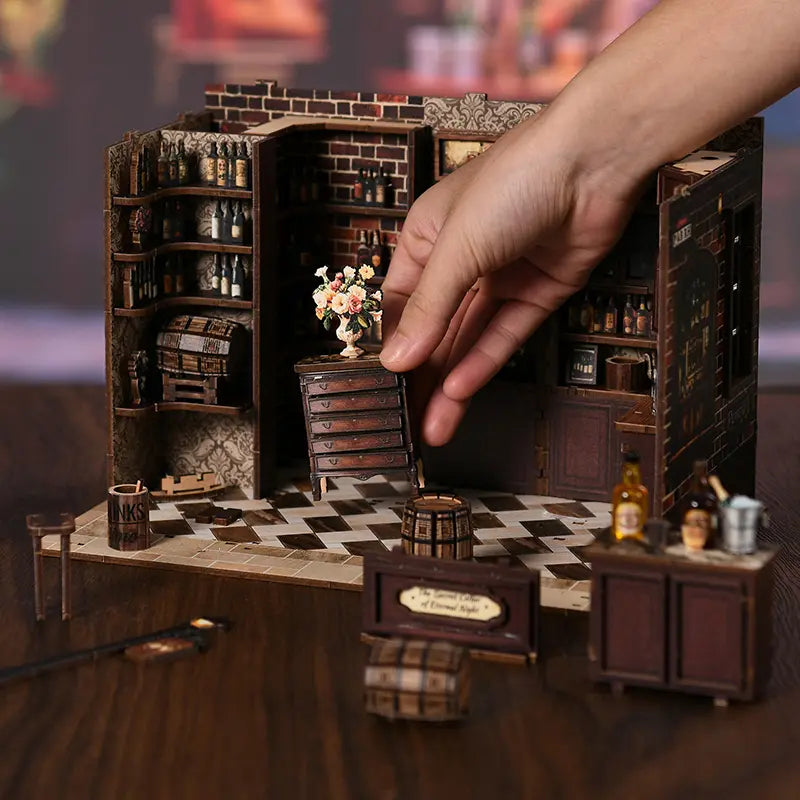 Corner Tavern DIY miniature assembly process – hands installing checkered floor tiles into wooden base frame, step-by-step craft kit for Victorian pub miniature diorama, ages 14 and up
